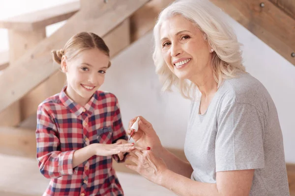 Vrolijke mooie vrouw haar kleindochters nagels schilderen — Stockfoto