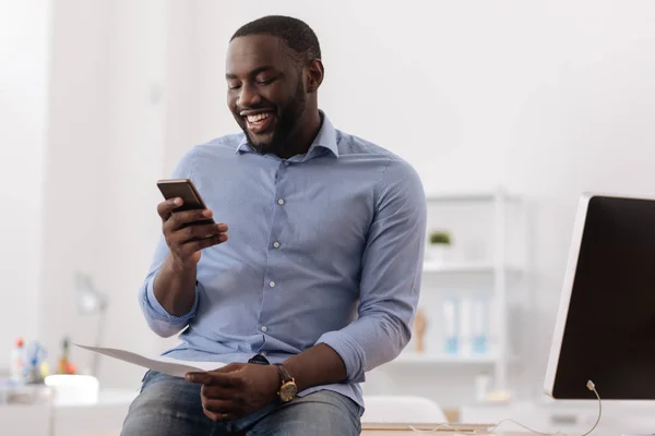 Alegre hombre agradable sosteniendo su teléfono inteligente —  Fotos de Stock