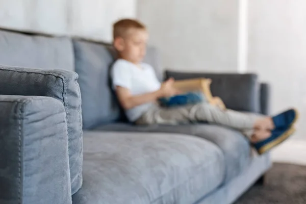 Pequeño niño dedicado sentado en un sofá — Foto de Stock