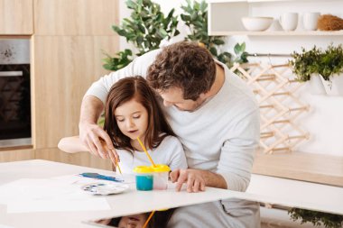 Father helping his daughter in painting clipart