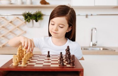 Smart little girl playing chess alone clipart
