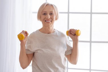 Happy female raising yellow dumbbells clipart