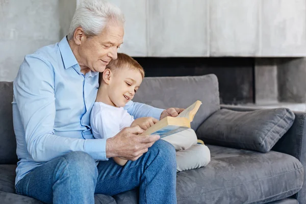 Diligente guapo abuelo leyendo para su nieto —  Fotos de Stock