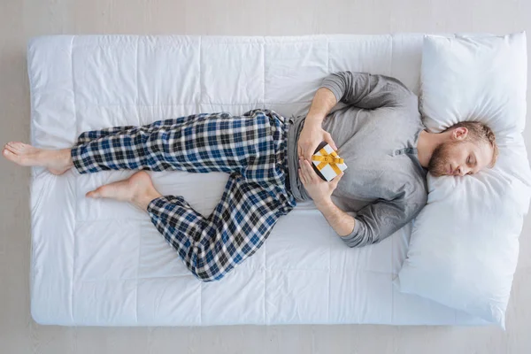 Tranquilo hombre guapo que tiene un regalo en sus manos — Foto de Stock