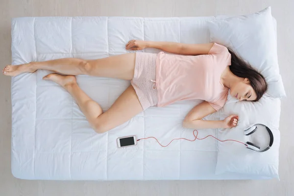 Pleasant young woman lying near her smartphone — Stock Photo, Image