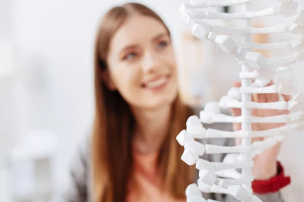 Charming lively woman examining the model of genome