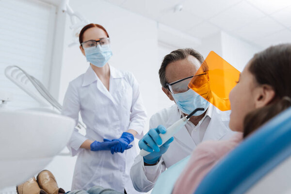 Компетентный стоматолог со специальными инструментами
