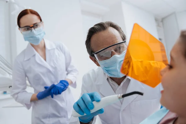 Uważny stomatologist za pomocą specjalnych urządzeń, badając zębów — Zdjęcie stockowe