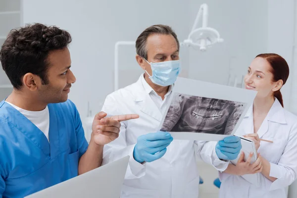 Уважний стоматолог, дивлячись на рентгенівське фото щелепи — стокове фото