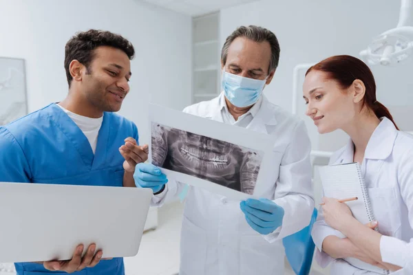 Uppmärksamma tandläkare i masken står mellan praktikanter — Stockfoto