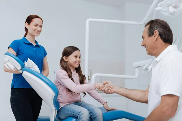 Dentista sorridente segurando a mão de seu paciente — Fotografia de Stock