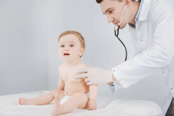 熟练掌握年轻的医生，在他小小的病人使用听诊器 — 图库照片