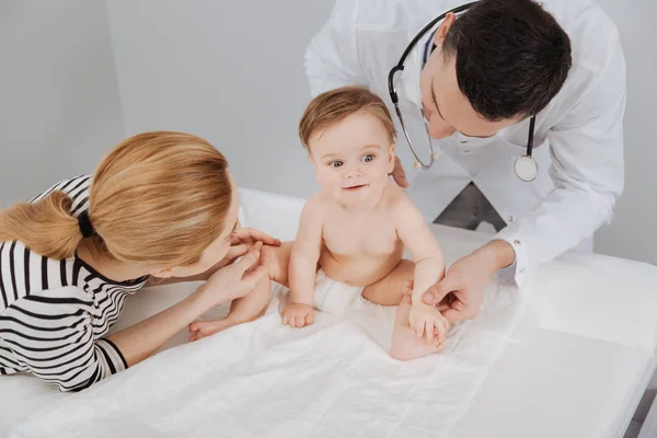 Geschäftiger Arzt und lustige Mutter, die Aufmerksamkeit auf entzückendes Baby richtet — Stockfoto