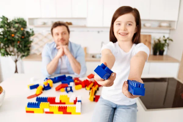 Sonriente chica llegar a fuera dos construcción conjunto piezas — Foto de Stock