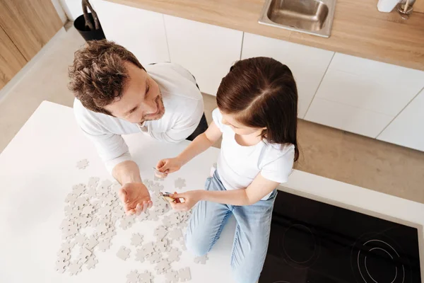 Little girl checking whether the puzzle pieces match — Stock Photo, Image