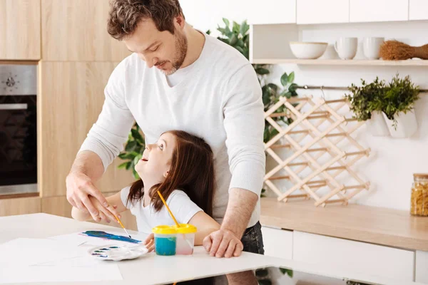 Father and daughter looking at each other while painting — Stock Photo, Image