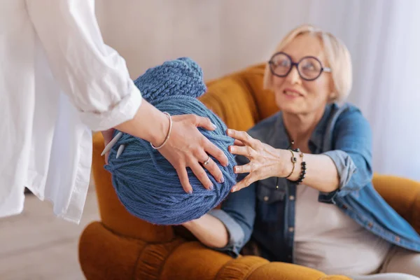 Крупним планом жіночі руки, які дають пряжу для її мами — стокове фото