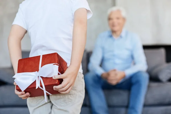 Loving adorable kid hiding a present for his grandpa Stock Photo