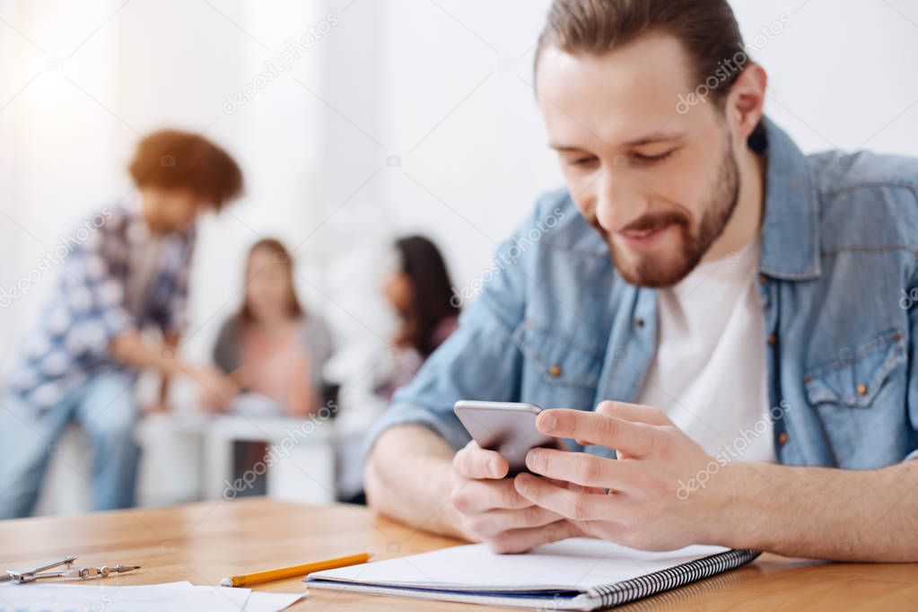 Savvy outgoing guy using a gadget while studying