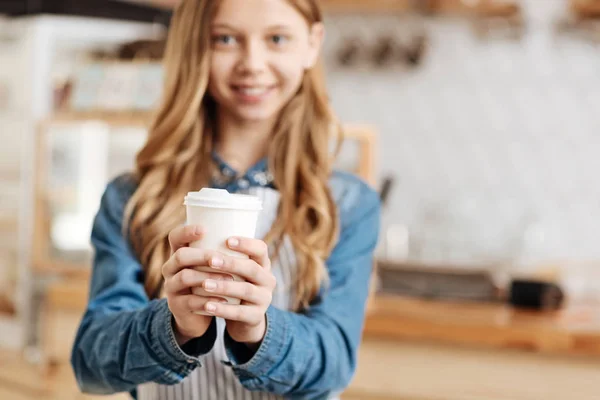 Hübsche Kaffeebar-Mitarbeiterin hält mit beiden Händen eine Kaffeetasse — Stockfoto