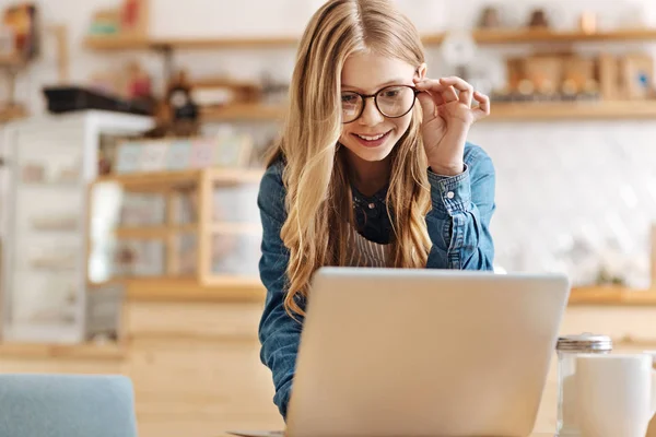 Vrij tienermeisje die op laptop werkt en glazen aan te passen — Stockfoto