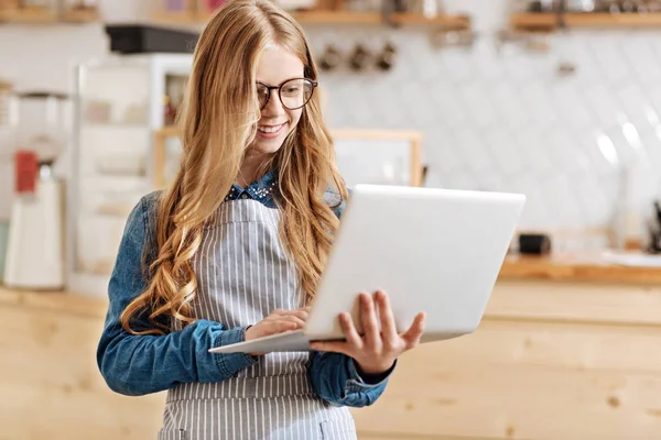 Szép fiatal barista állandó és a gazdaság egy laptop — Stock Fotó