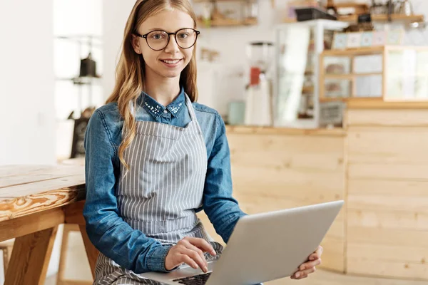 Aangename jonge barista poseren met een laptop op haar schoot — Stockfoto