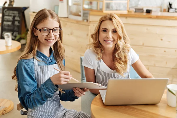 Blond mamma och hennes dotter som poserar vid bordet — Stockfoto