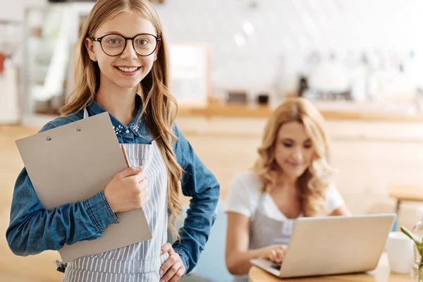 Smiling joyful girl posing with a sheet holder in a cafe — Stock Photo, Image