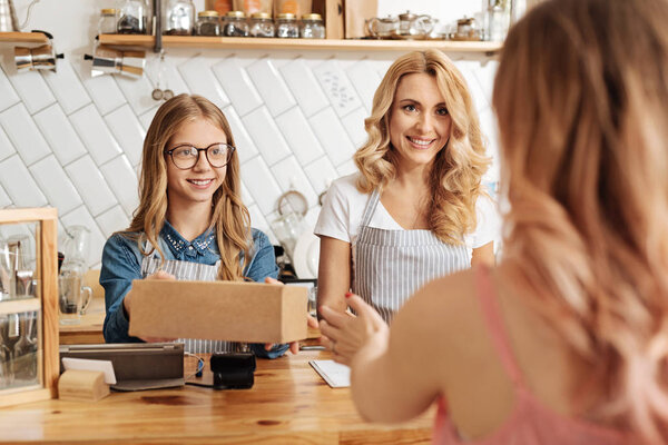 Pleasant baristas selling a box of cookies to the customer