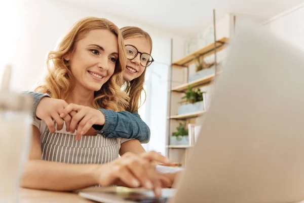 Liebevolle Tochter umarmt ihre arbeitende Mutter von hinten — Stockfoto