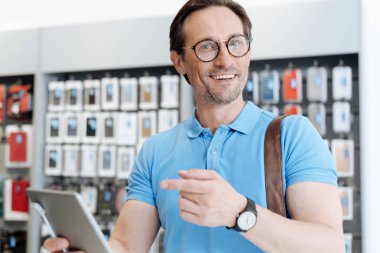 Tablet doğru işaret ve kameraya gülümseyen hayran adam