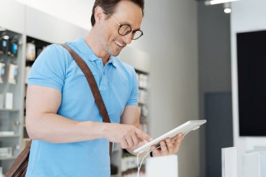 Parlak adam geniş tablet için alışveriş yaparken sırıtarak