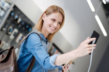 Şablon telefon ile kendi kendine portre çekerken gülen genç bayan