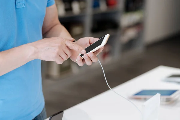 Sidovy på man tittar på cellphone på elektronikaffär — Stockfoto