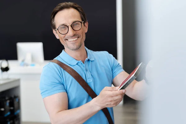 Ritratto del cliente maschio che sorride ampiamente mentre tiene la custodia del telefono — Foto Stock