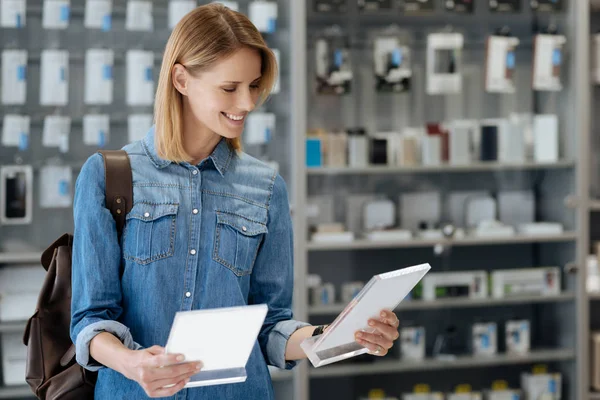 Stralende vrouwelijke shopper vergelijken van twee platen van product informatie — Stockfoto