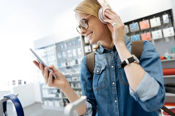 Studentessa provare cuffie modello presso negozio di elettronica — Foto Stock