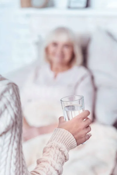 Любящая женщина держит стакан воды для стареющей матери — стоковое фото