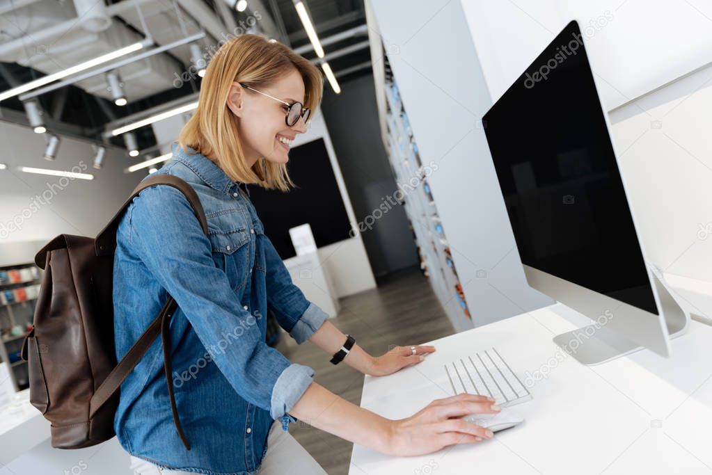 Side view of blonde woman trying out computer at store