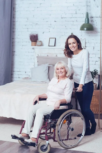 Lachende dochter helpen uitgeschakeld moeder thuis — Stockfoto