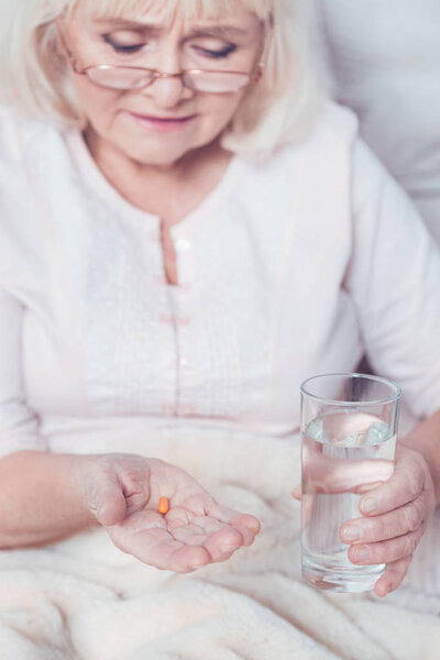 Careful retired woman taking pills at home