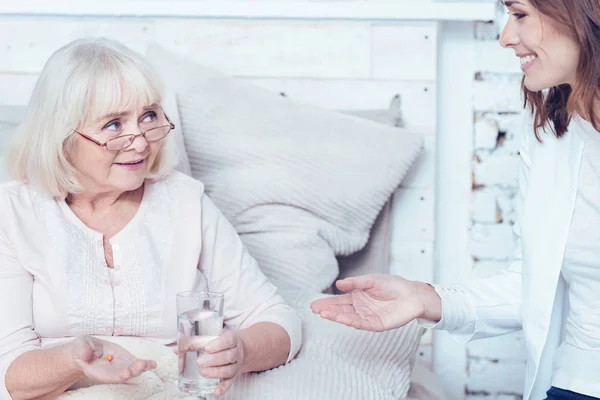 Vriendelijke welzijnswerk assistent adviseren pillen aan patiënt thuis — Stockfoto