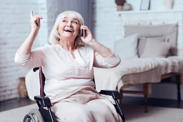 Positiv behinderte ältere Frau, die zu Hause mit dem Smartphone spricht — Stockfoto