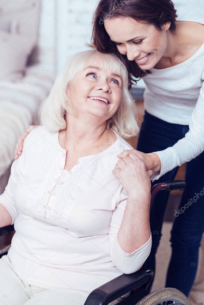 Helpful daughter taking care of disabled mother at home