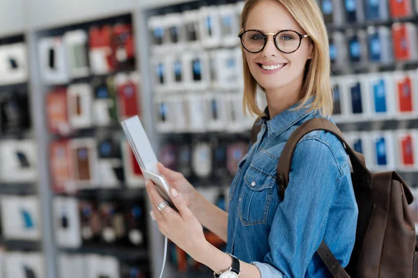 Stralende blonde dame holding mockup telefoon en glimlachend in de camera — Stockfoto