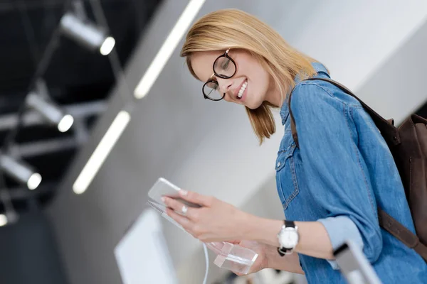 Låg vinkel skott av positiv kvinna som tittar på mallen cellphone — Stockfoto