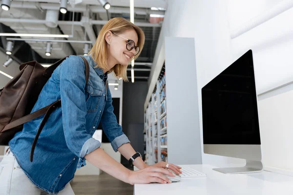 Visão lateral da mulher radiante testando as capacidades tecnológicas do computador — Fotografia de Stock