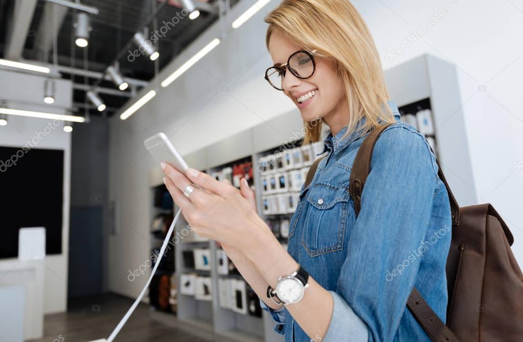 Excited female customer testing smartphone at store display