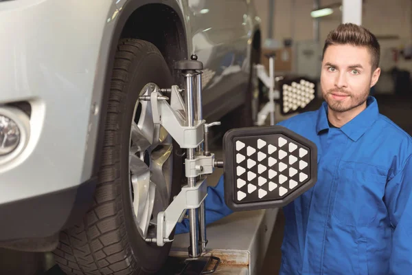 Precise jovem mecânico regulando pneus de um carro — Fotografia de Stock